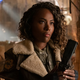 Kayla holding a gun while wearing a bomber jacket.